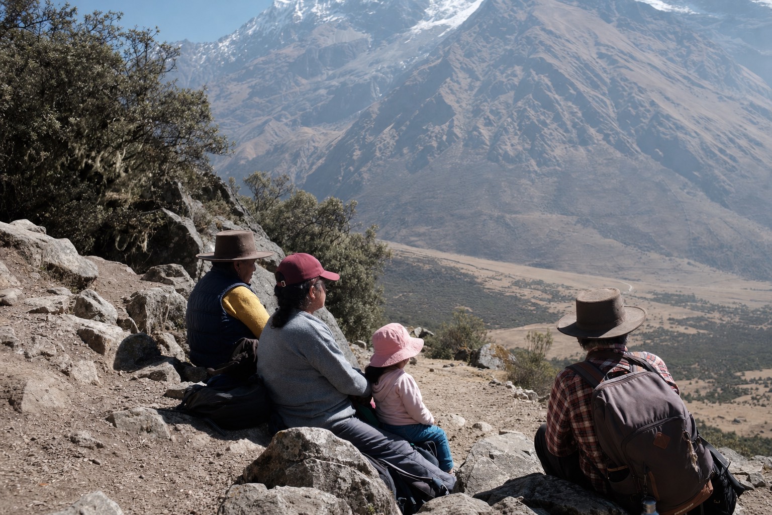 Family with a child and grandparents resting beside the rocky trail above Soraypampa