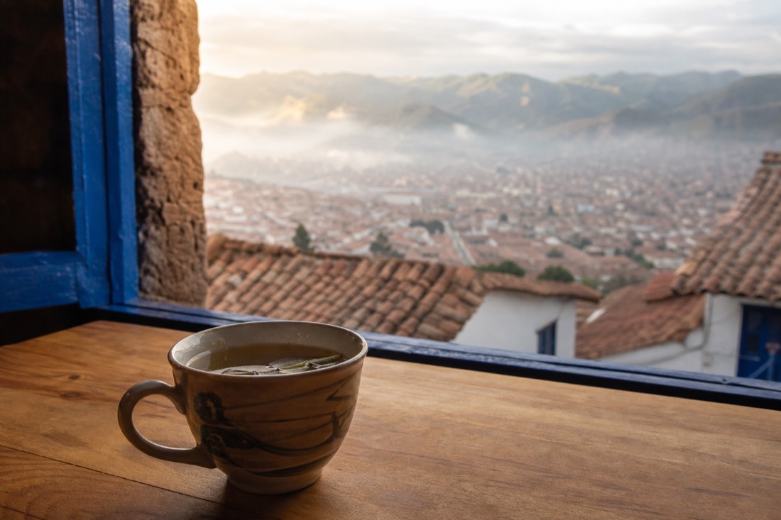 Cup of coca leaf tea on a wooden table in a Cusco guesthouse at dawn