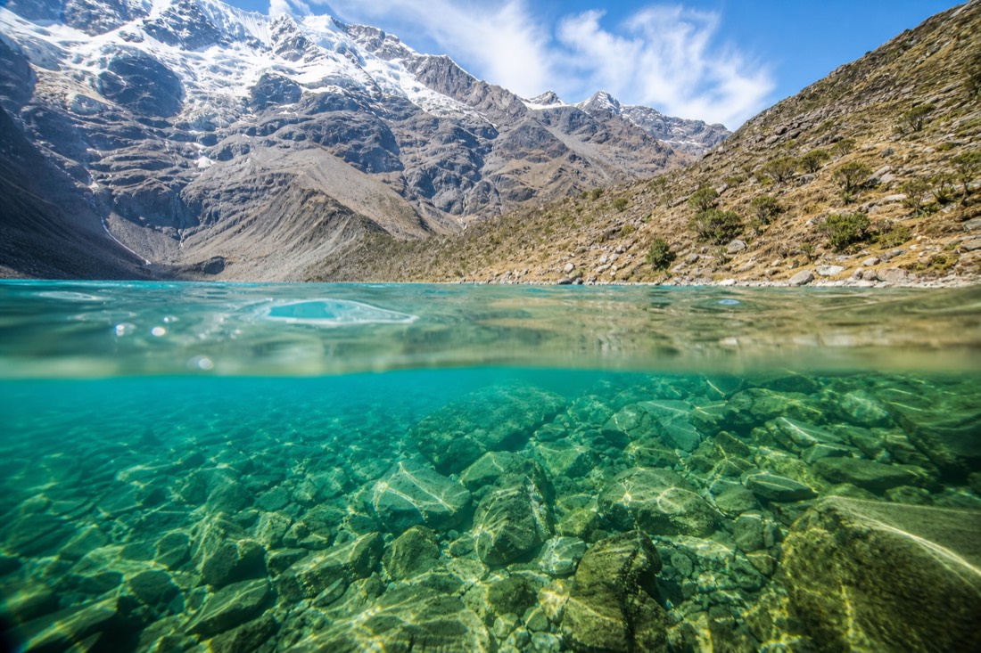 Split view of Humantay Lake's turquoise water and Rainbow Mountain's striped mineral ridge